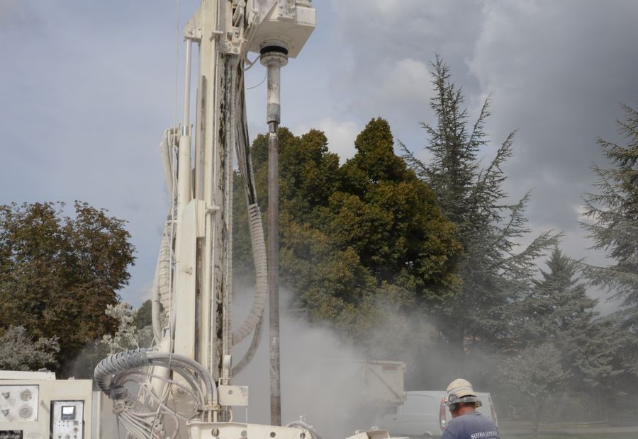Drilling rig running a bit deeper on a Central Texas lot with dust rising off the hole